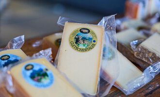 A selection of packaged cheese on a table. The cheese has various labels and packaging.