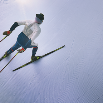 A skier glides down a perfectly groomed slope. The clear, snow-covered surroundings radiate calm and focus.