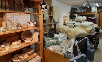 A cozy shop with wooden shelves full of handmade products. In the background, there are high-quality wool products and decorations. | © Abler Mitbringsel Riezlern | Veronika Senn