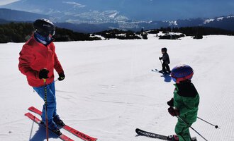 A group of skiers on a snow-covered slope. Impressive mountains can be seen in the background. | © Austrian Ski- & Service Ranch | Trixi Leitner
