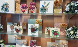 Eine Darstellung von verschiedenen schön verpackten Geschenken auf einem Regal. Die Geschenke sind mit bunten Schleifen und Dekorationen versehen. | © Kleinwalsertal Tourismus | N. Lughammer