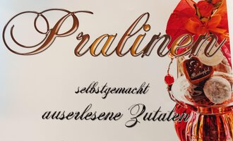 Ein ansprechendes Bild von Pralinen in einer dekorativen Verpackung. Der Text betont, dass sie selbstgemacht und aus erlesenen Zutaten hergestellt sind. | © Kleinwalsertal Tourismus | N. Lughammer