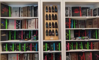 A bookshelf with many notebooks in various colors and designs. Below are colored pens and other stationery. | © Chrömle Schönes aus Filz | N. Lughammer