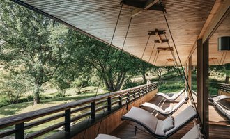 A relaxing veranda with modern loungers overlooking a green garden. The wooden ceiling and the natural surroundings create a peaceful atmosphere. | © Naturhotel Chesa Valisa | Heldentheater
