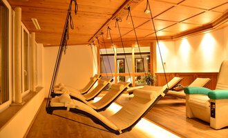 A cozy relaxation room with hanging loungers and warm light. The wooden ceiling creates a relaxing atmosphere. | © Hotel Alpenstüble KG | Manuel Riezler