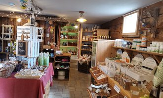 Ein gemütlicher Laden mit Holzwänden, der verschiedene Produkte wie Geschenke und lokale Lebensmittel anbietet. Das Ambiente ist einladend und freundlich. | © Dies & Das Hofladen | V. Wächter