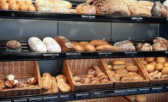A shelf full of fresh rolls and breads in various shapes. The selection ranges from seed rolls to classic breads. | © Ehrat´s Backmanufaktur | Veronika Senn