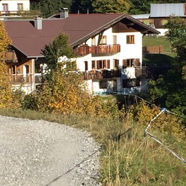 Ein idyllisches Haus inmitten von buntem Herbstlaub. Der Garten ist gut gepflegt und das Gebäude hat einen traditionellen alpinen Stil. | © Gasthof Café Alpenwald | Thorsten Alpenwald
