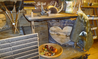 A cozy wooden shelf with various decorative objects. Among them are a fruit bowl, hand tools, and a rolled-up fabric.