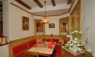 Ein gemütlicher Restaurantbereich mit roten Polstern und einem Holzstuben-Design. Die warmen Lichter und die Dekoration schaffen eine einladende Atmosphäre. | © Michl das Steakhaus | Johannes Littich