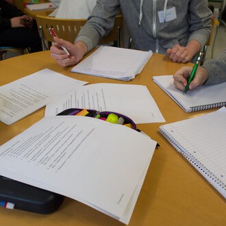 Eine Gruppe von Personen arbeitet an einem Tisch mit Notizen und Schreibmaterialien. Auf dem Tisch liegen verschiedene Blätter und Notizbücher. | © Kleinwalsertal Tourismus