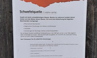 Ein Informationsschild über die Schwefelquelle auf dem Walser Kulturweg. Es gibt Hinweise und Details zur Quelle sowie zu den Umgebungen. | © Kleinwalsertal Tourismus | Veronika Senn