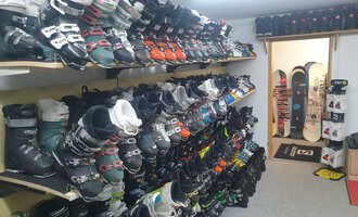 Ein Skiverleih mit vielen Skischuhen auf Regalen. Im Hintergrund ist ein Bereich für Snowboards zu sehen. | © IFA Hotel Alpenrose