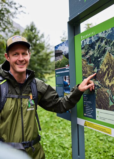 A man explains a map to a group of children in Kleinwalsertal, providing educational information about the nature reserve. | © Kleinwalsertal Tourismus eGen • Photographer: Oliver Farys