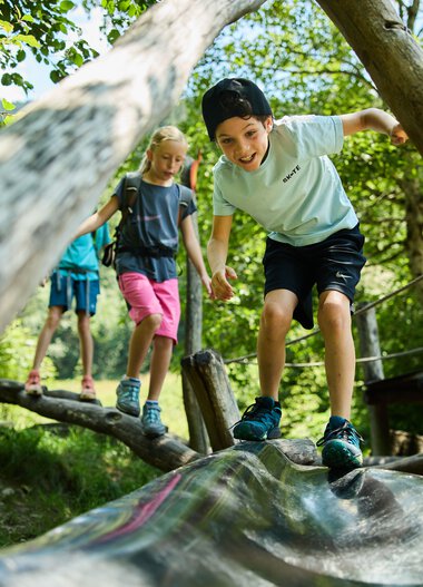 Children playing on a wooden bridge in the forest, laughing and exploring nature in Kleinwalsertal. | © Kleinwalsertal Tourismus eGen • Photographer: Oliver Farys