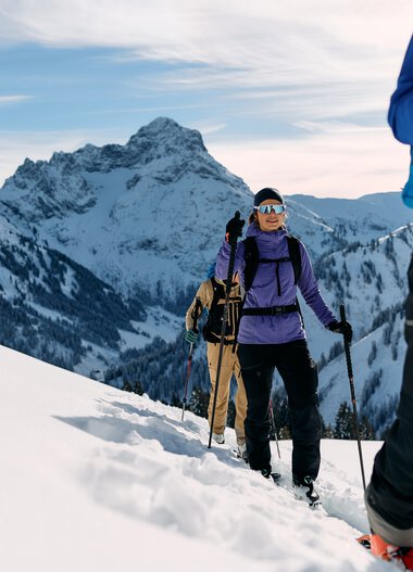 Gruppe von Skitourengehern unterwegs in verschneiter Berglandschaft im Kleinwalsertal, mit Rucksack und Skistöcken. | © Kleinwalsertal Tourismus eGen • Fotograf: Oliver Farys