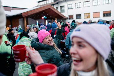 Menschen feiern im Freien bei einem Winterevent mit Musik und gemeinsamer Freude, viele tragen Winterkleidung und Mützen. | © Kleinwalsertal Tourismus eGen • Fotograf: Oliver Farys