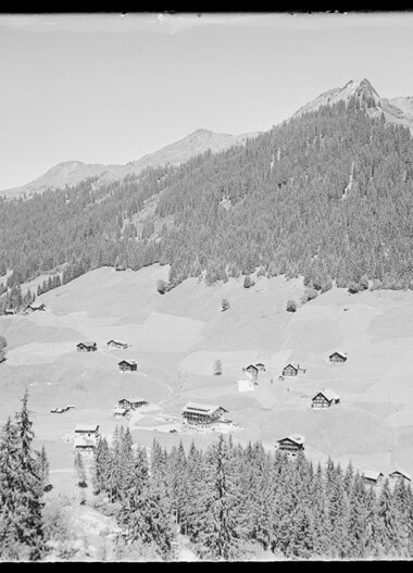 Historical black-and-white photo of Baad in Kleinwalsertal, featuring mountains and scattered houses in the landscape. | © Kleinwalsertal Tourismus eGen • Karl Max Kessler Archiv