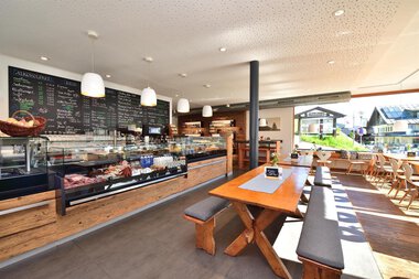 Interior of a farm shop with a display counter, tables, seating area, plenty of natural light, modern decor. | © Kleinwalsertal Tourismus eGen • s´Hirscheck
