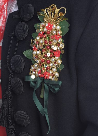 Close-up of a traditional costume from Kleinwalsertal featuring a floral brooch and colorful embroidery. | © Kleinwalsertal Tourismus eGen • Photographer: Christoffer Leitner