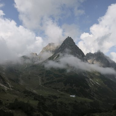 Berglandschaft mit schroffen Gipfeln, teilweise von Wolken bedeckt, in den Bergen. Eine beeindruckende Naturaufnahme. | © Kleinwalsertal Tourismus eGen • Fotograf: Antje Pabst