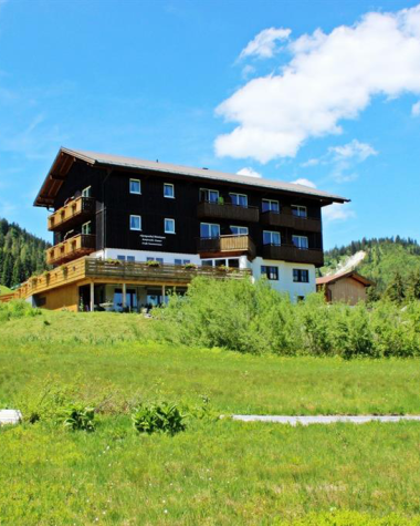 Modern building in a rural setting in Kleinwalsertal, surrounded by green meadows and mountains, under a sunny sky. | © Kleinwalsertal Tourismus eGen