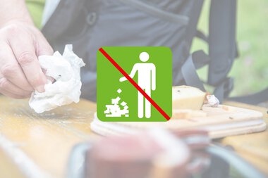 Verboten: Kein Müll auf den Boden werfen. Bild zeigt eine Hand, die Papier auf einen Tisch wirft, mit einem Symbol für kein Wegwerfen. | © Kleinwalsertal Tourismus eGen